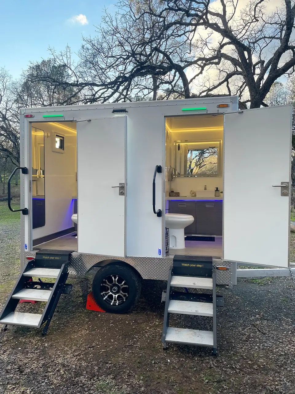 Luxury restroom trailer lit up in the evening with both doors open