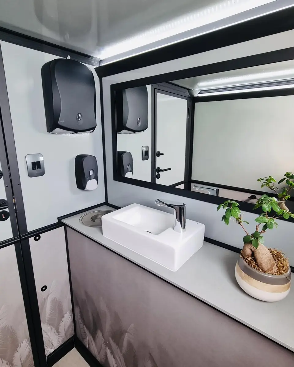 Restroom trailer vanity with mirror, paper towel dispenser and plant