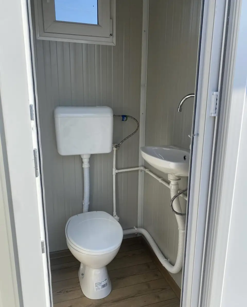 Inside a VIP restroom cabin with a flush toilet, tank and small sink